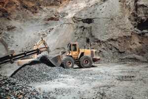 Máquina carregadeira movimentando pedras em mina a céu aberto, destacando robustez e eficiência das soluções da TCINOX para mineração e desgaste abrasivo.