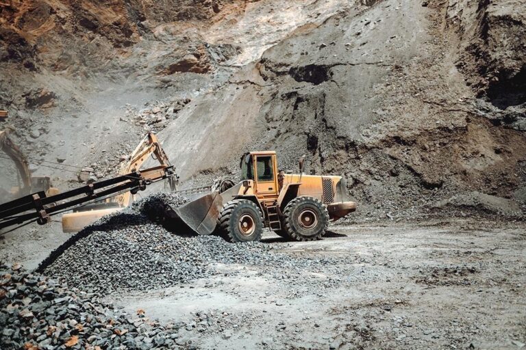 Máquina carregadeira movimentando pedras em mina a céu aberto, destacando robustez e eficiência das soluções da TCINOX para mineração e desgaste abrasivo.